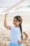 Cute Hispanic girl playing with toy plane on beach