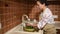 Cute housewife carefully rinses freshly picked organic cucumbers under tap water, standing at the sink in the kitchen