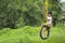 Cute indian child playing on swing made by tyre and rope on tree at green field