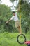 Cute indian child playing on swing made by tyre and rope on tree at green field