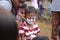 A cute Indonesian boy\'s face is full of wheat while competing to take coins from a food container called Nyiru