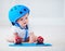 Cute infant baby girl in protective helmet outfit ready to ride skateboard, extreme sport concept