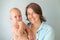 Cute infant baby on mothers hands on a gray background. Mother hugging baby with love. Motherhood concept. Unconditional