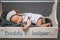 cute infant baby showing thumb up while sleeping in wooden toolbox with daddys