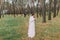 Cute innocent bride in white gown with fur halfcoat wait for her handsome groom on fores trail