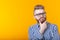 Cute intelligent young man with a beard and with glasses poses on a yellow background with copy space and thinks about