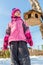 Cute ittle caucasian girl in sport winter jacket having fun playing outdoors with snow. Bird feeder on tree on background. Winter