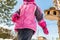 Cute ittle caucasian girl in sport winter jacket having fun playing outdoors with snow. Bird feeder on tree on background. Winter