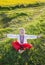 Cute joyful boy 5 years old in national Ukrainian clothes, embroidered shirt and red trousers sits barefoot on grass