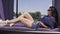 Cute joyful woman with dark long hair and long bare legs resting in the sun lying on a lounger. Woman in sunglasses