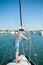 Cute kid in captain hat standing on white yacht board in sea bay in summer