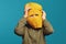 Cute kid looking at camera thru yellow knitted thief mask,  over blue