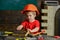 Cute kid playing with tool set. Little carpenter working with wooden block. Small boy in workshop