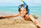 Cute kid in scuba mask laying on sandy beach