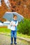 Cute kid with umbrella in park, rainy weather