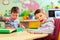 Cute kids with special needs playing with developing toys while sitting at the desk in daycare center