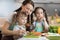 Cute kids tasting vegetables as they prepare a meal with their mother in the kitchen