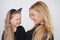 Cute kind caucasian blonde mom and daughter posing on white background. a parent and a child experience love and hug.