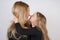 Cute kind caucasian blonde mom and daughter posing on white background. a parent and a child experience love and hug.