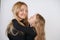 Cute kind caucasian blonde mom and daughter posing on white background. a parent and a child experience love and hug.