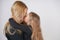 Cute kind caucasian blonde mom and daughter posing on white background. a parent and a child experience love and hug.