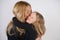 Cute kind caucasian blonde mom and daughter posing on white background. a parent and a child experience love and hug.