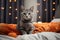 Cute kitten sits on the room sofa near jack-o'-lantern pumpkin