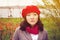 A cute Korean girl wearing beige coat and red beret hat outdoors near the lake in autumn.