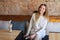 Cute lady sitting on chair near wooden table and holding cup of coffee.n