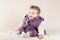 Cute laughing baby girl in purple jacket on knitted