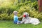 Cute liitle baby boy is playing with pet toy and dog outside