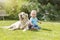 Cute liitle baby boy is posing with a lying dog outside