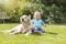 Cute liitle baby boy is waving at the camera posing with a dog outside