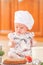 Cute liitle girl in chef`s hat sitting on the kitchen floor soil