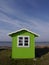 A cute lime-green beach hut with background of blue sea and sky