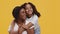 Cute little african american girl embracing her lovely mother, woman enjoying daughter hugs, orange studio background