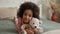 Cute little African American girl hugs her favorite teddy bear. Teenage girl in pajamas lies on bed in bedroom with