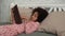 Cute little African American girl reads a book with fairy tales and falls asleep. Teenage girl in pajamas lies on bed in