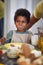 Cute little african boy smiling at table, with milk moustache