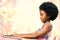 Cute little african girl with afro hairstyle typing on laptop.