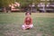 Cute little Asian 1 - 2 years old toddler baby girl child smiling at camera, barefoot practices yoga & meditating outdoors on