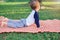 Cute little Asian 18 months / 1 year old toddler baby boy child practices yoga in cobra Pose and meditating outdoors on nature in