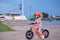 Cute little Asian 2 years old toddler girl child wearing safety helmet learning to ride first balance bike, kid cycling at the