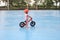 Cute little Asian 2 years old toddler girl child wearing safety helmet learning to ride first balance bike, kid cycling at the