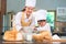 Cute little Asian boy and beautiful mother sifting dough flour with sifter sieve colander in home kitchen on table for prepare to