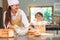 Cute little Asian boy and beautiful mother sifting dough flour with sifter sieve colander in home kitchen on table for prepare to