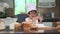 Cute little Asian boy with eyeglasses, chef hat and apron exciting with eggs for  first time experience to baking bakery in home k