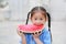 Cute little Asian child girl in school uniform enjoy eating fresh sliced watermelon