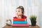 Cute little asian girl gazing and looking at empty space against books on table