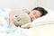 Cute little asian girl sleep and hug teddy bear on bed.